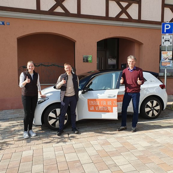 E-Carsharing Igersheim Eine Frau und zwei Männer stehen vor uns neben einem Auto mit Stadtwerk Tauberfranken - Branding und lächeln in die Kamera.