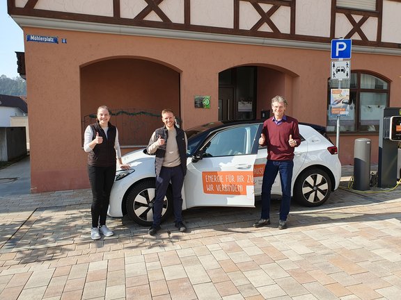 E-Carsharing Igersheim Eine Frau und zwei Männer stehen vor uns neben einem Auto mit Stadtwerk Tauberfranken - Branding und lächeln in die Kamera.