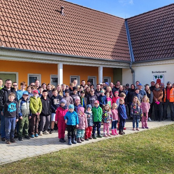 Kehrtwende-Aktion Viele Personen von jung bis alt stehen vor einem Gebäude und lächeln in die Kamera. Die Sonne scheint.